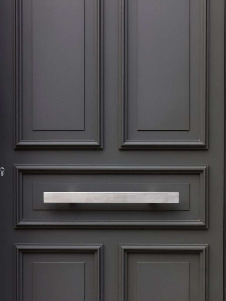 Moderne aluminium voordeur in donkergrijs met strakke inox handgreep, geplaatst door Bruvo.